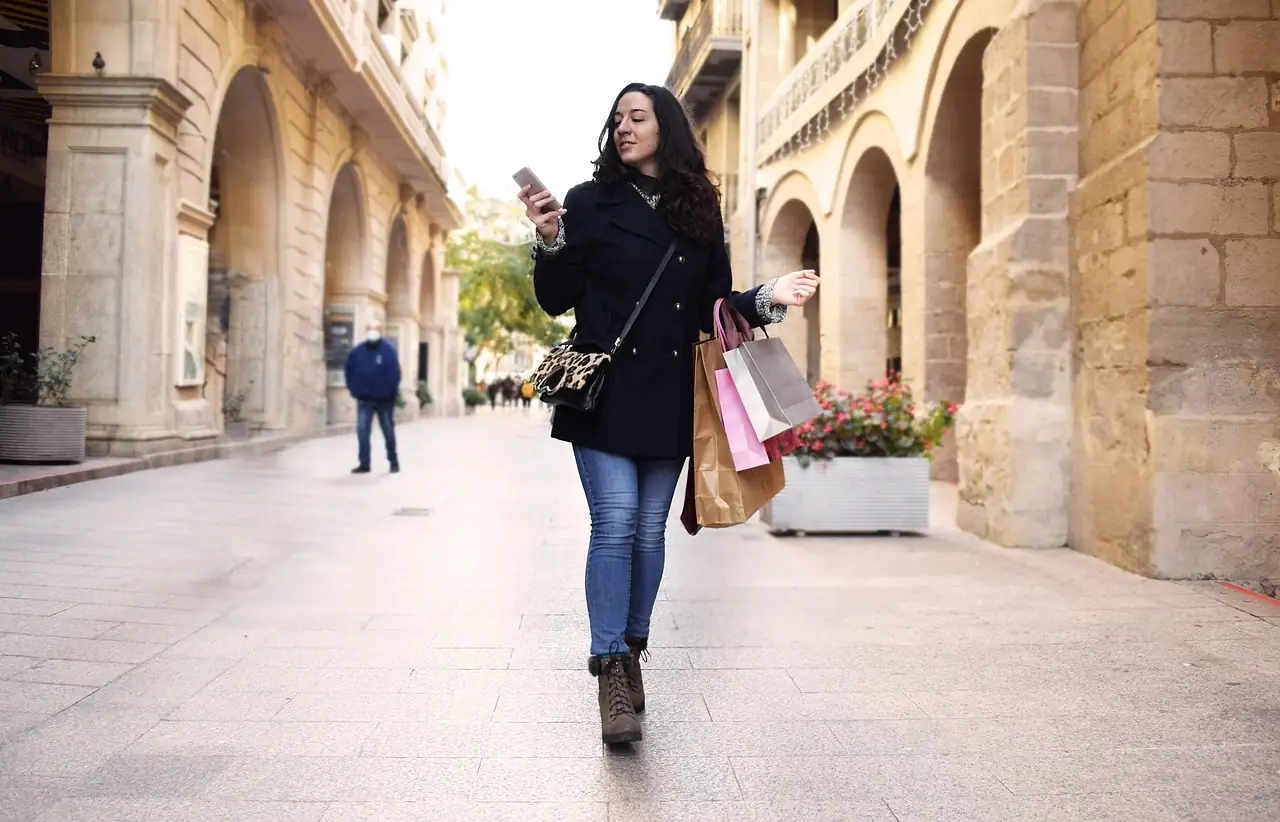 Une femme regarde son téléphone dans une rue commerçante